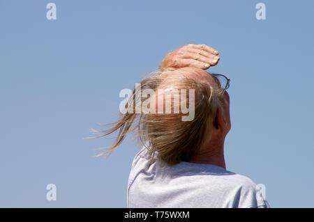 White middle aged or old male with comb over hairstyle blowing in the wind. Man outside on a windy day with bald pate and long side hair blown around Stock Photo