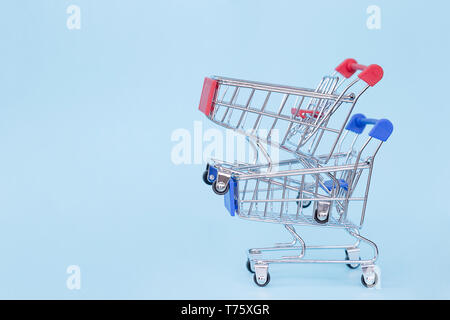 Empty grocery cart on wheels on a blue background with free space for text Stock Photo