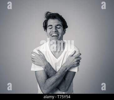 Black and white portrait of young sensitive man feeling in love looking happy, shy and lucky. Isolated on neutral background. In people positive human Stock Photo