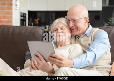 Senior couple with digital tablet at home. Grandparents using social media. Stock Photo