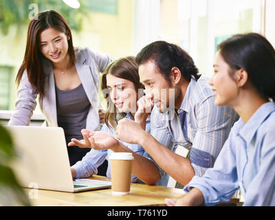 team of four business people meeting in office using laptop computer. Stock Photo