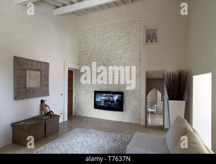 interiors shots of a living room with concrete floor and stone wall the ceiling is made of wood Stock Photo