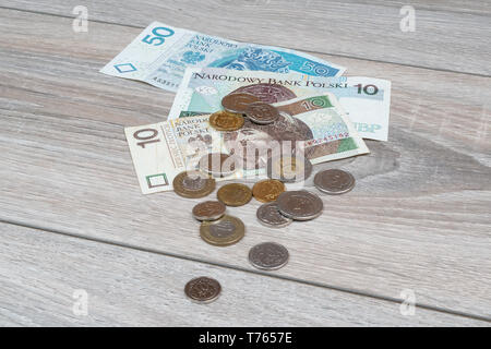 some banknotes and some coins of Polish zloty on a wooden table Stock Photo