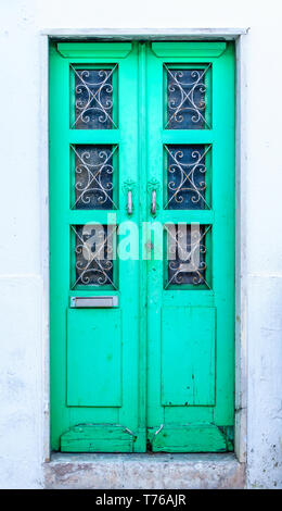 Traditional Portuguese front door with vibrant green color in weathered facade - vertical portrait orientation Stock Photo