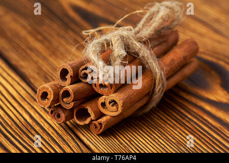 Bundle of cinnamon tied with a rope on a wooden background close-up. Stock Photo