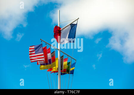 Flag pole in Gustavia, St Barts with numerous flags on display against a blue sky Stock Photo