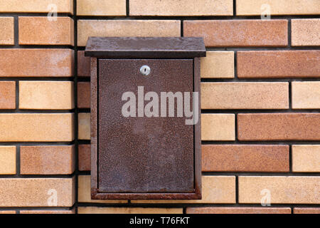 Brown mailbox on wall of building outdoors Stock Photo