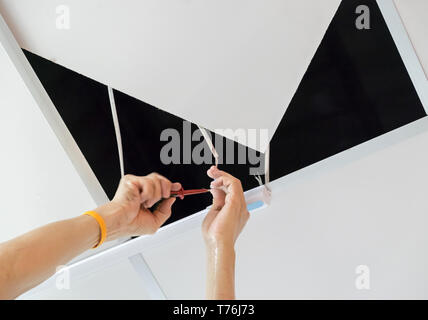 Adult hand male is repairing wire lamp on ceiling Stock Photo
