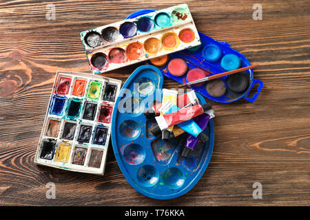 Tubes and palettes with paints on wooden table Stock Photo