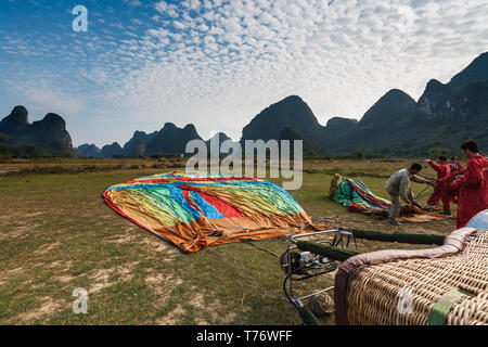 Workers prepare to inflate hot air balloon so they can take tourist on rides over the mountains and river valley in Yangshao, China Stock Photo
