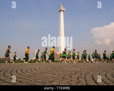 View of many men running around the National Monument  in Merdeka Square Jakarta, Indonesia Stock Photo