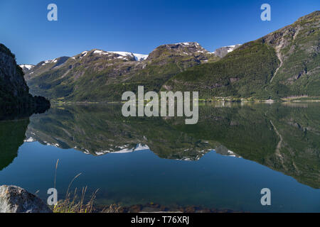 Reflection of the Folgefonna glaciers in the clear, calm waters of Hardangerfjord, Norway Stock Photo