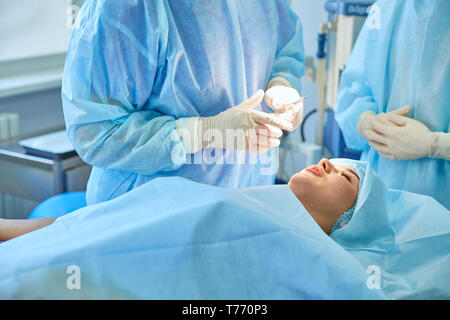 Several doctors surrounding patient on operation table during their work. Team surgeons at work in operating room.