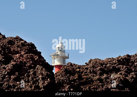 The red-white lighthouse of the point of the Teno Mountains stands in a volcanic landscape, the 'Punta de Teno'  Loose volcanic rock Stock Photo