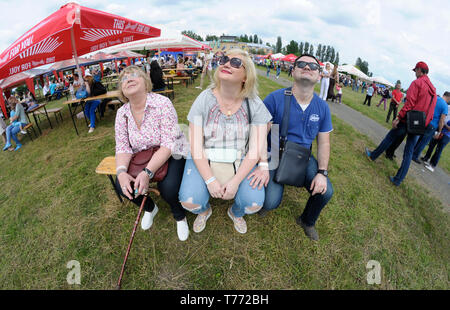 Man and two women in sunglasses sitting on a bench and looking at the sky. 7-th Air show. June 21,2018. Kiev, Ukraine Stock Photo