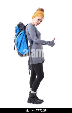 Cool backpacker young hipster woman with rucksack hitchhiking and looking at camera. Full body isolated on white background. Stock Photo