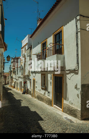Old white terraced houses with peeling plaster in a narrow alley at Elvas. A gracious city on the easternmost frontier of Portugal. Stock Photo