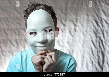 a boy in a light t-shirt leaned against the face of a white mask Stock Photo