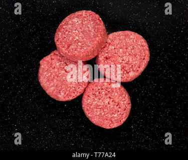 Fresh raw prime black Angus beef burger patties on black stone background. Stock Photo