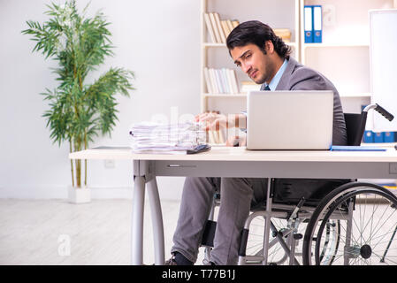 Young handsome employee in wheelchair at the office Stock Photo