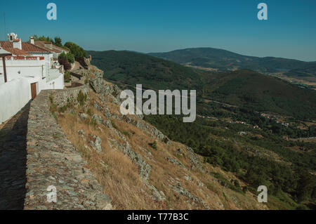 Old houses and stone breastwork over ridge, with mountainous landscape at Marvao. A medieval hamlet perched on a crag in Portugal. Stock Photo