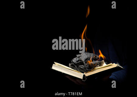 A man holds a burning book in his hand. Stock Photo