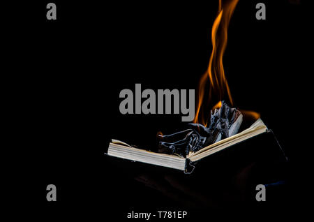 A man holds a burning book in his hand. Stock Photo
