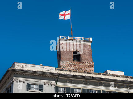 Genoa, Genova, Italy, waving flag, Croce di San Giorgio (red cross on white background) atop of Torre Grimaldina, Palazzo Ducale tower, Doge's Palace Stock Photo