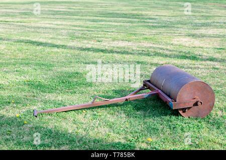 Steel old grass roller on grass yard - rusty tool Stock Photo