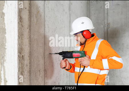 A Worker man drilling in concrete on a construction site Stock Photo
