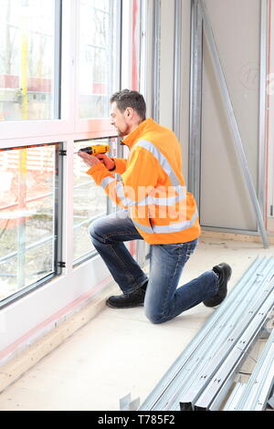 A Worker Man installing a wooden window on construction site Stock Photo