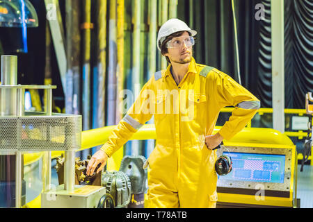 Young man in a yellow work uniform, glasses and helmet in industrial environment,oil Platform or liquefied gas plant Stock Photo