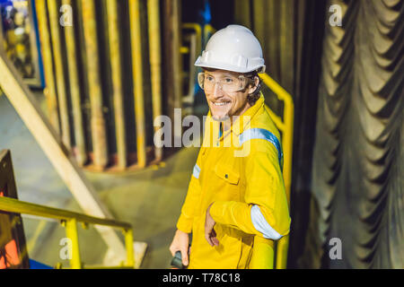 Young man in a yellow work uniform, glasses and helmet in industrial environment,oil Platform or liquefied gas plant Stock Photo