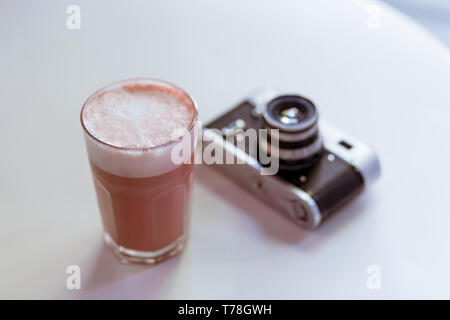 Pink hipster coffee cappucciono on the white table with old fashioned retro style film photo camera Stock Photo