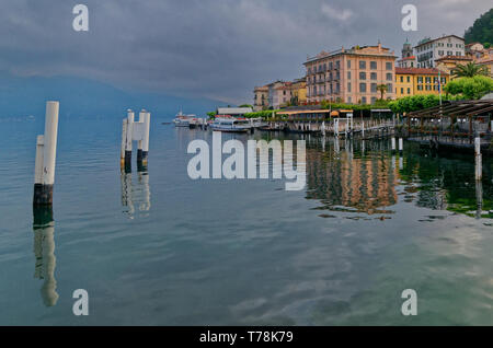 A view across the harbour to the Hotel Metropole and other colourful buildings of Bellagio, with reflections in the water of Lake Como Stock Photo