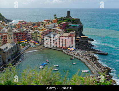View of the vibrant colours of Vernazza and its harbour from the Cinque Terre trail on a bright day with a clear blue sky Stock Photo