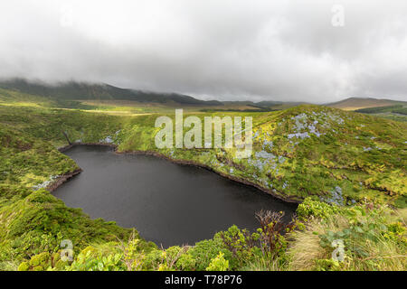 The dark crater lake, Lagoa Comprida on the island of Flores in the Azores. Stock Photo