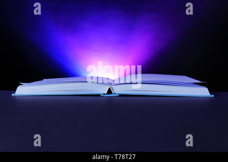 Open book with glowing on dark background Stock Photo