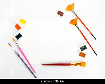 Sheet of paper with brushes and paints on white background Stock Photo