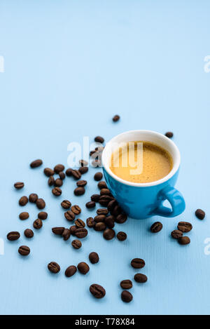Blue espresso cup with coffee on blue pastel background with beans around Stock Photo