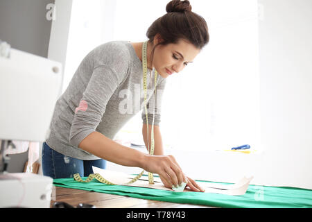 Young female tailor working with sewing pattern in atelier Stock Photo