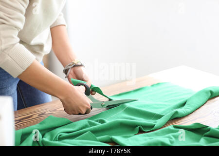 Young female tailor cutting fabric in atelier Stock Photo
