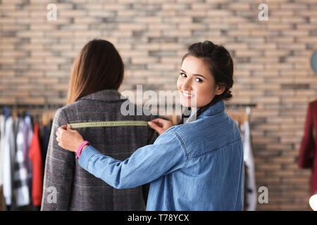 Young female tailor working with client at the final fitting in atelier Stock Photo