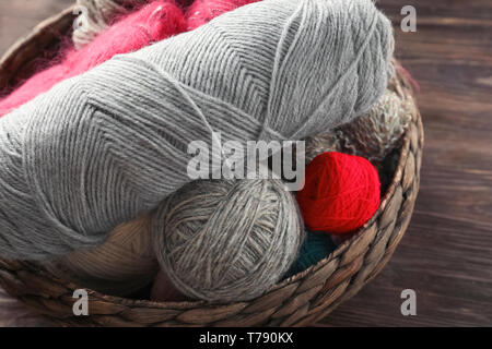 Wicker basket with knitting threads on wooden table Stock Photo