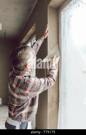 Diligent plasterer working on a window opening Stock Photo