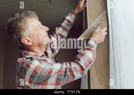 Diligent plasterer working on a window opening Stock Photo