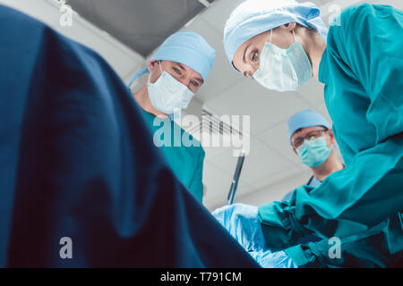 Team of surgeons in operation room during surgery Stock Photo