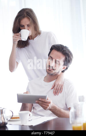 Couple having breakfast at home and using tablet Stock Photo