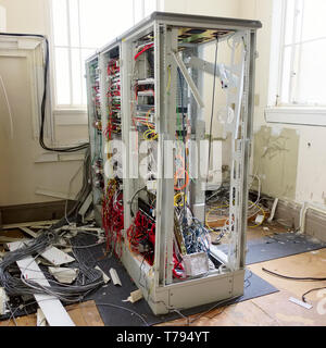 Server frame hardware rack and loose cables in communications room removed in derelict office building Stock Photo