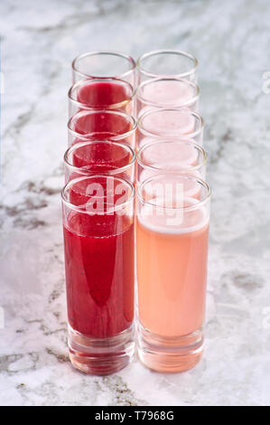 two rows of alcohol shot cocktails. coral and red colored drinks. vertical Stock Photo